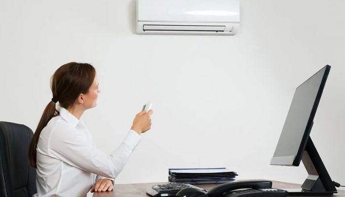 Mulher em um escritório ligando o ar-condicionado