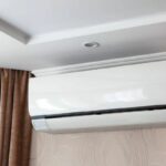 Foto de um ar-condicionado branco do lado de um cortina